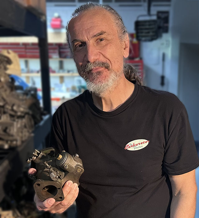 Rusty holding a Marvel-Schebler DLTX in his rebuilding shop
